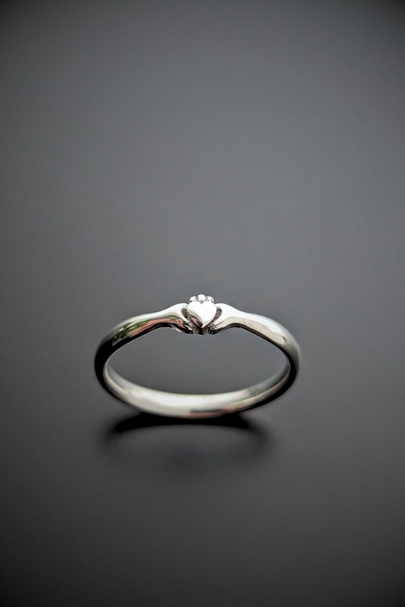 An Ceann beag, a unique Claddagh ring in silver displayed on a black background