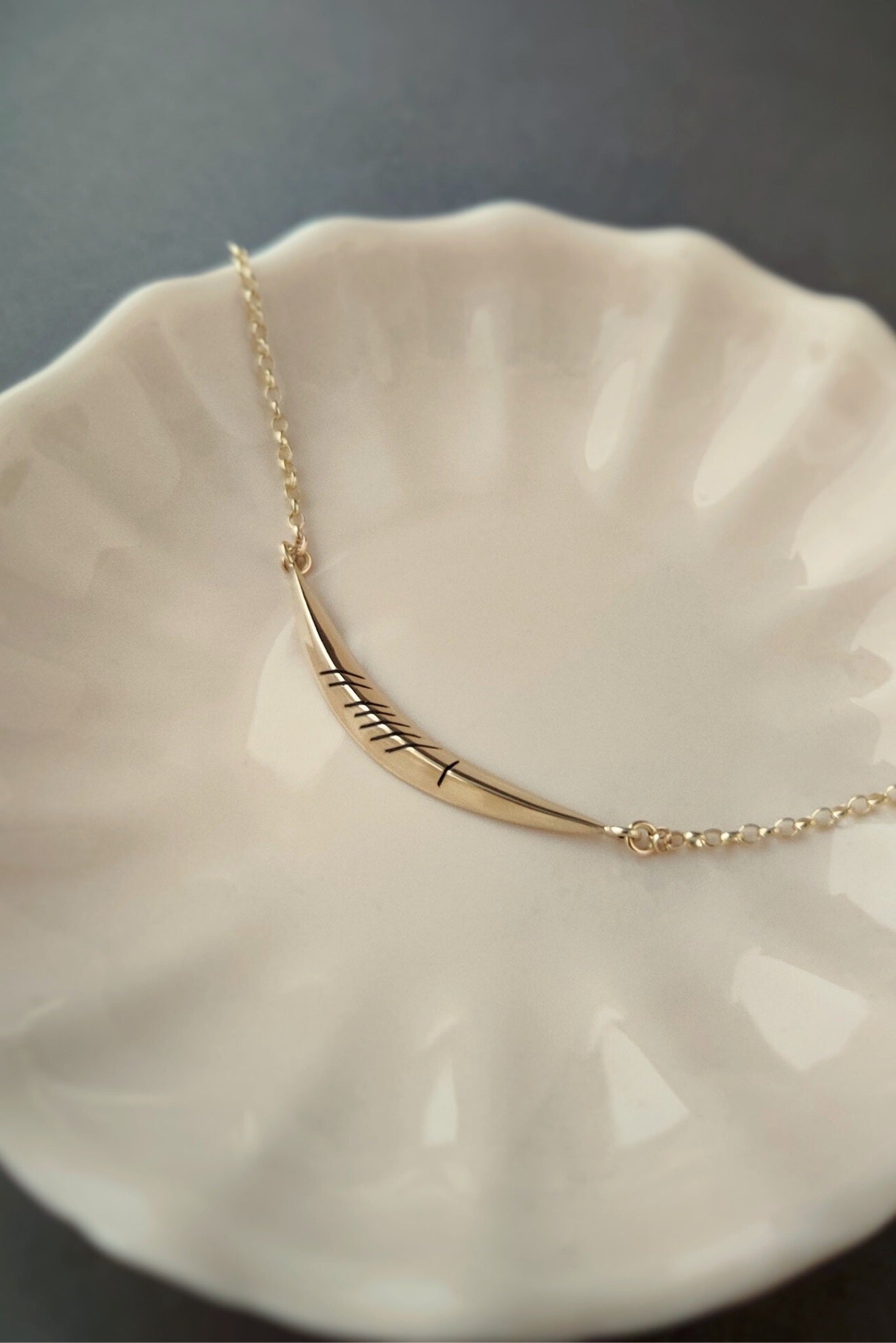 gold curved gra necklace on a plate